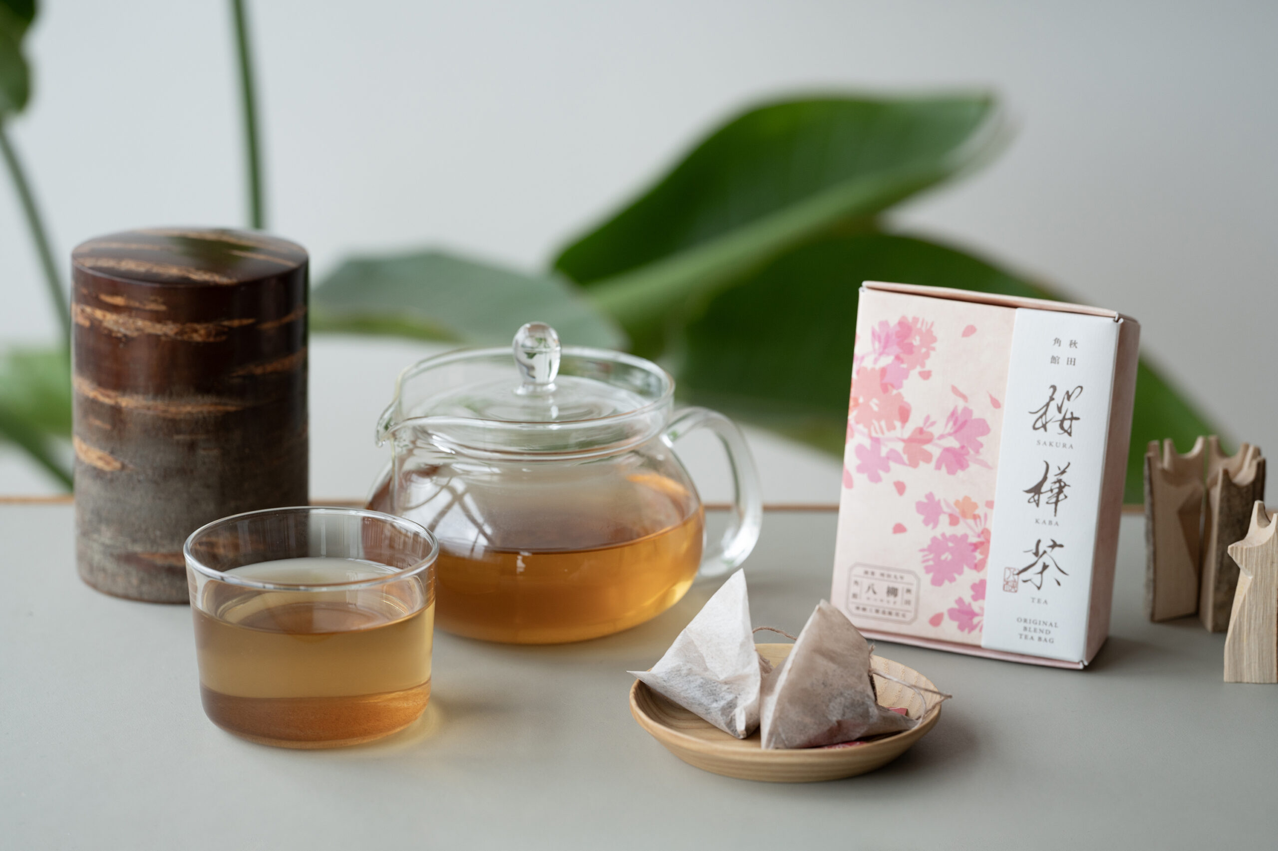 桜樺茶のパッケージと、ガラスの急須で淹れたお茶