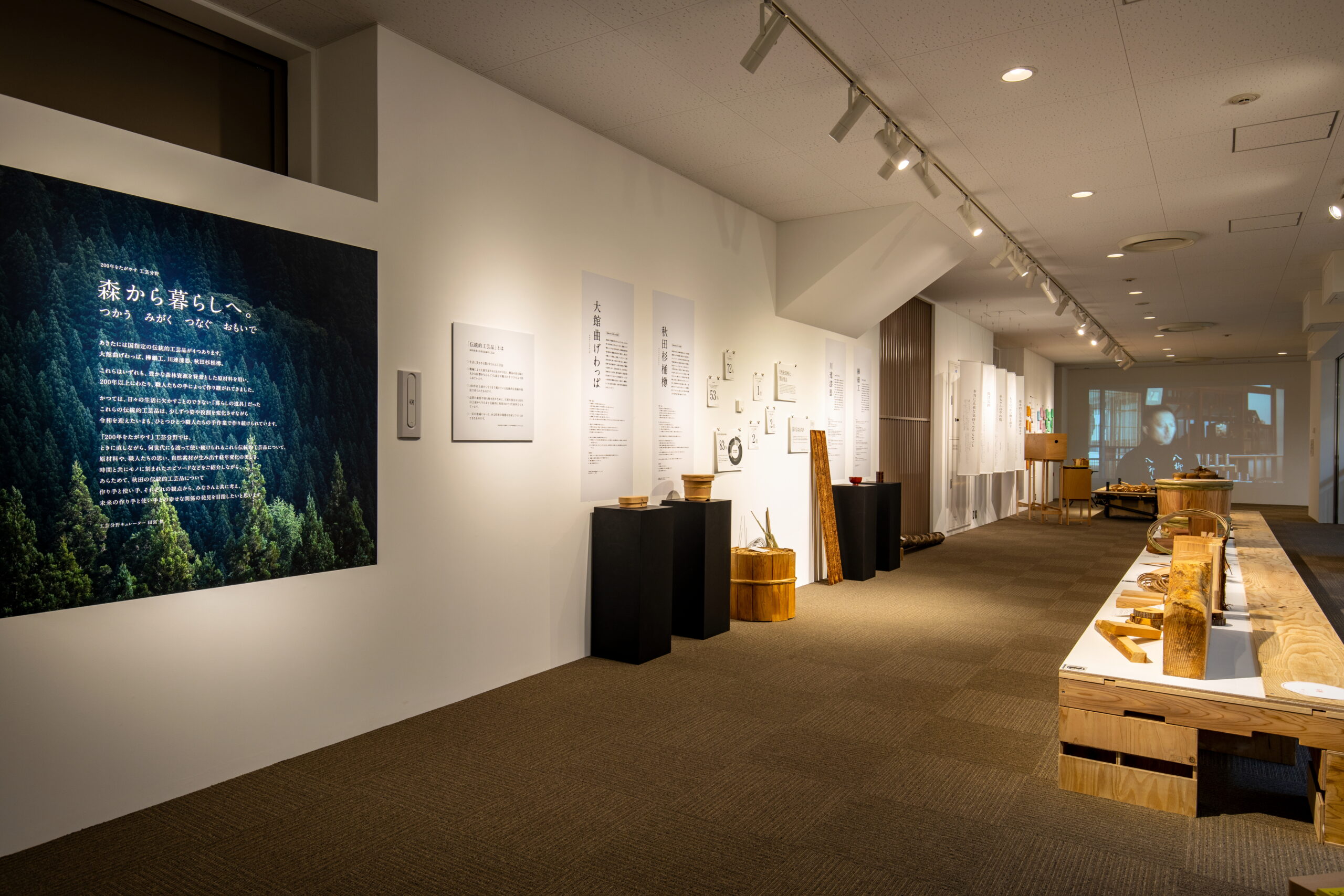 「森から暮らしへ」というテーマテキストと大館曲げわっぱ、秋田杉樽などの展示什器
