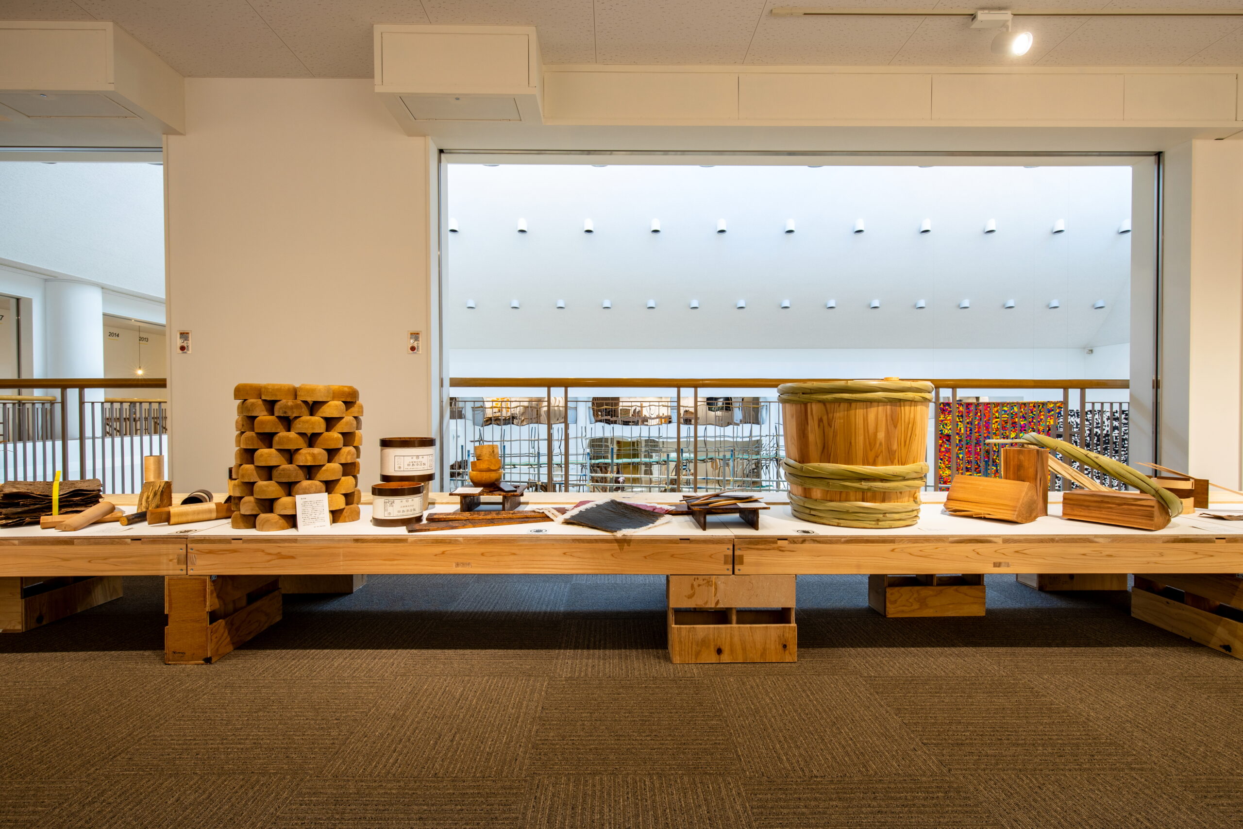 長机に並ぶ樽・木箱・かご等、多様な伝統工芸品の展示風景