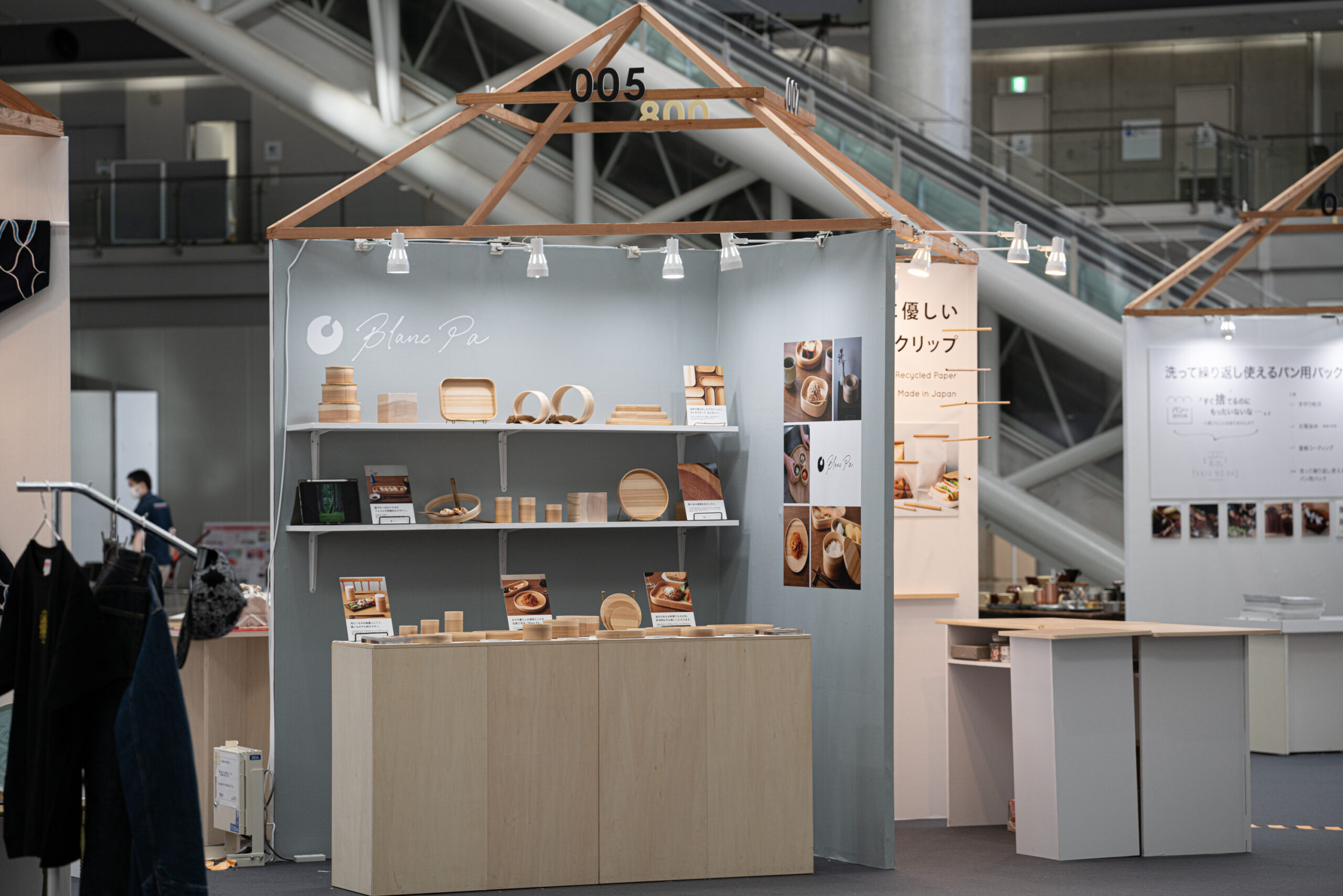 グレートーンの壁面に木製什器と製造過程のパーツを配したBlanc Paの展示ブース正面