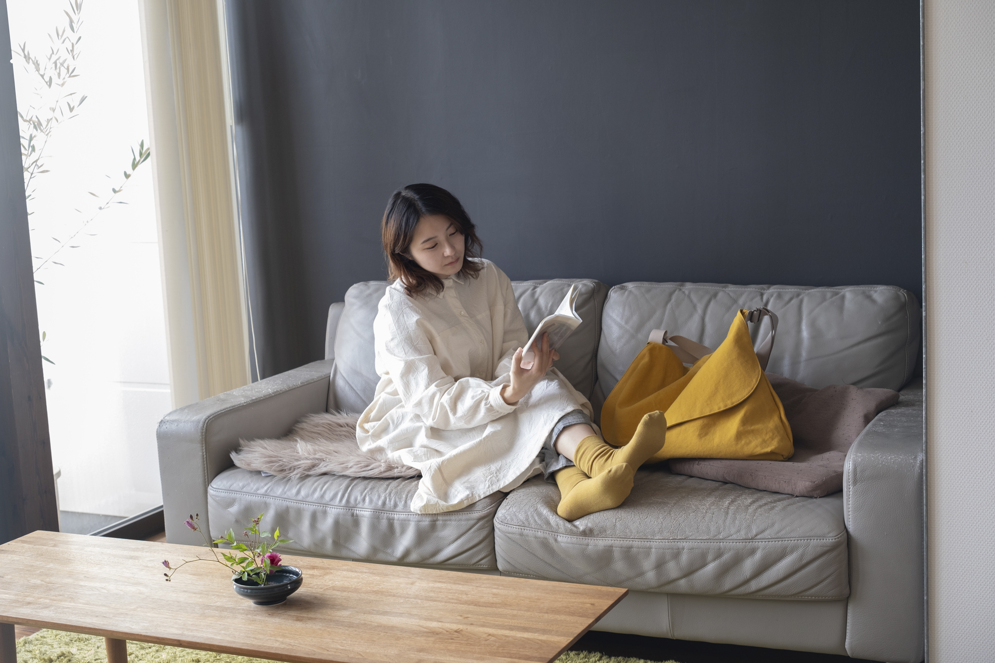 ソファでくつろぎながらギフトアイテムを手にする女性