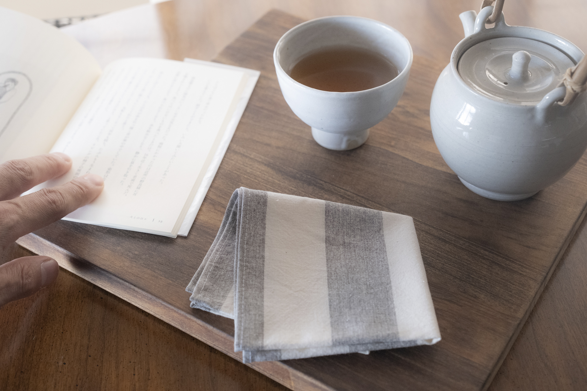 木のテーブルに置かれたお茶とストライプ柄の布